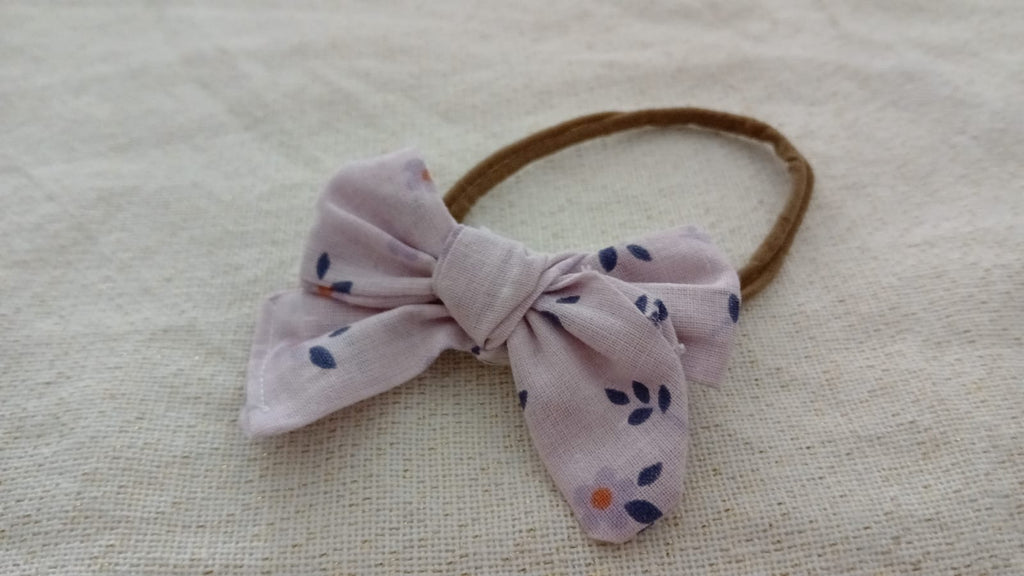 Paarse haarband met een blauwe strik van stof met bloemenprint.
