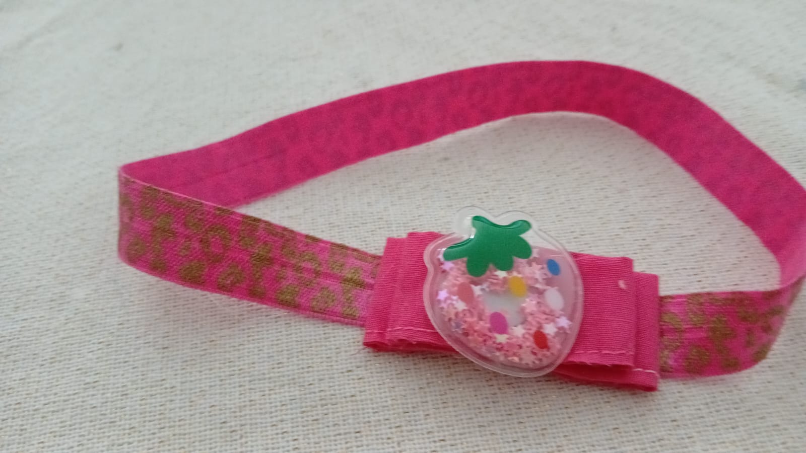 Roze haarband met aardbei in het midden.